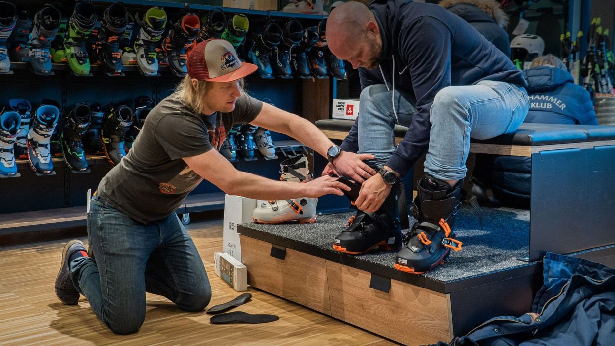 Medewerker knielt om skischoenen aan te passen bij een klant