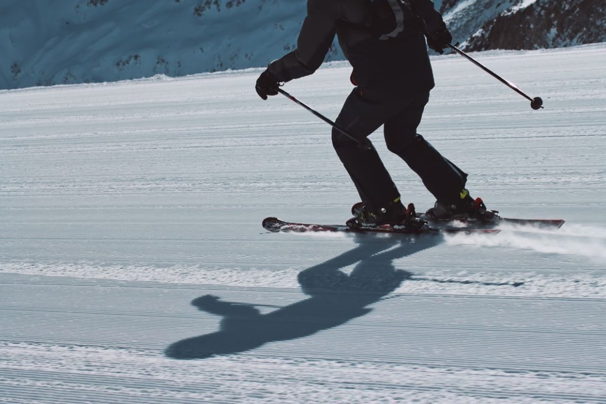 Benen van een skiër met zijn schaduw in de sneeuw
