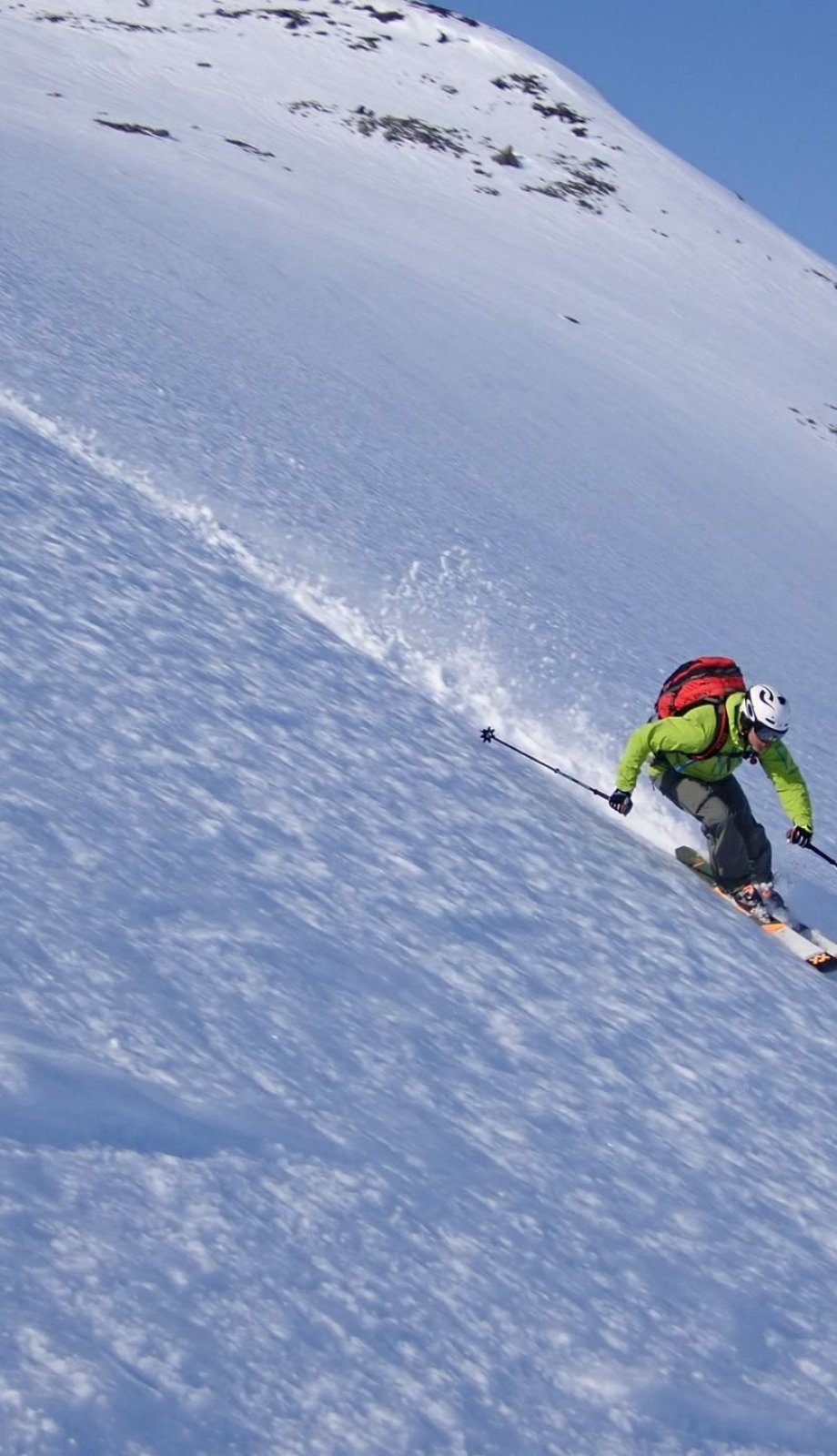 Skiër op een steile piste onder een blauwe lucht