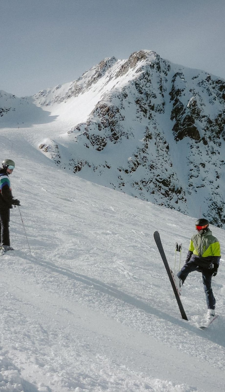 Twee skiërs op de piste met besneeuwde bergen op de achtergrond